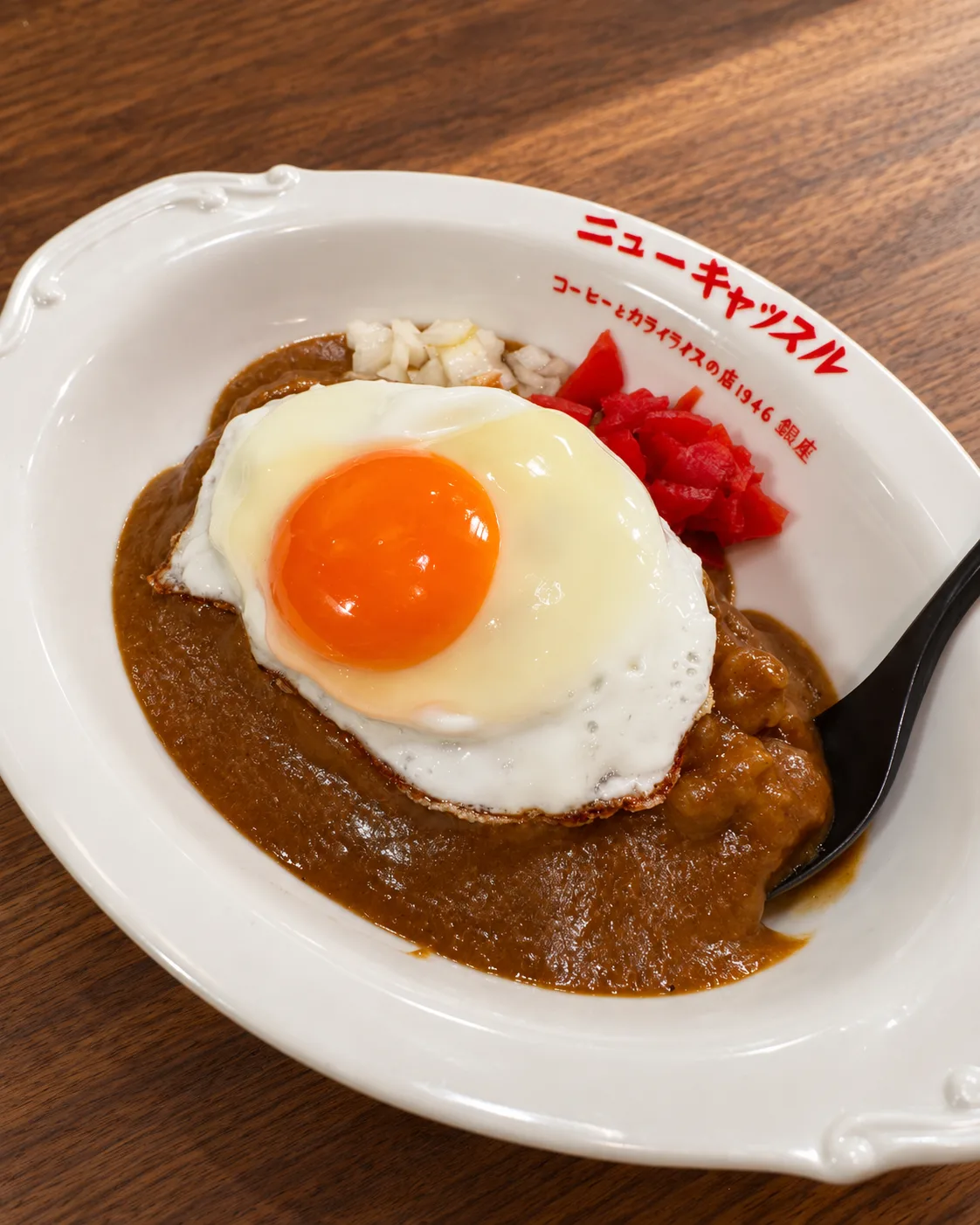 縁に店名の入った白い楕円の皿に盛った、目玉焼きをのせたカライライス